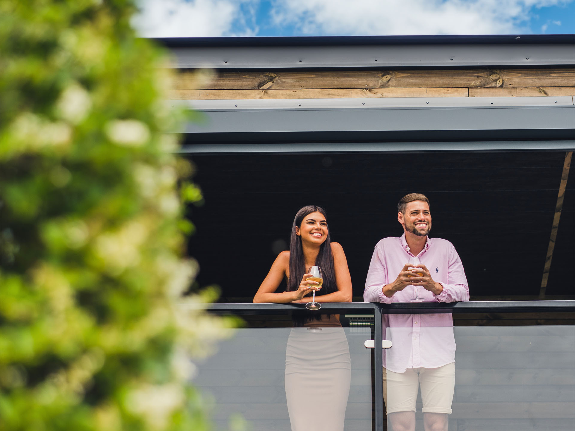 A woman and man leaning on the rail of the roof terrace looking onto the vineyard