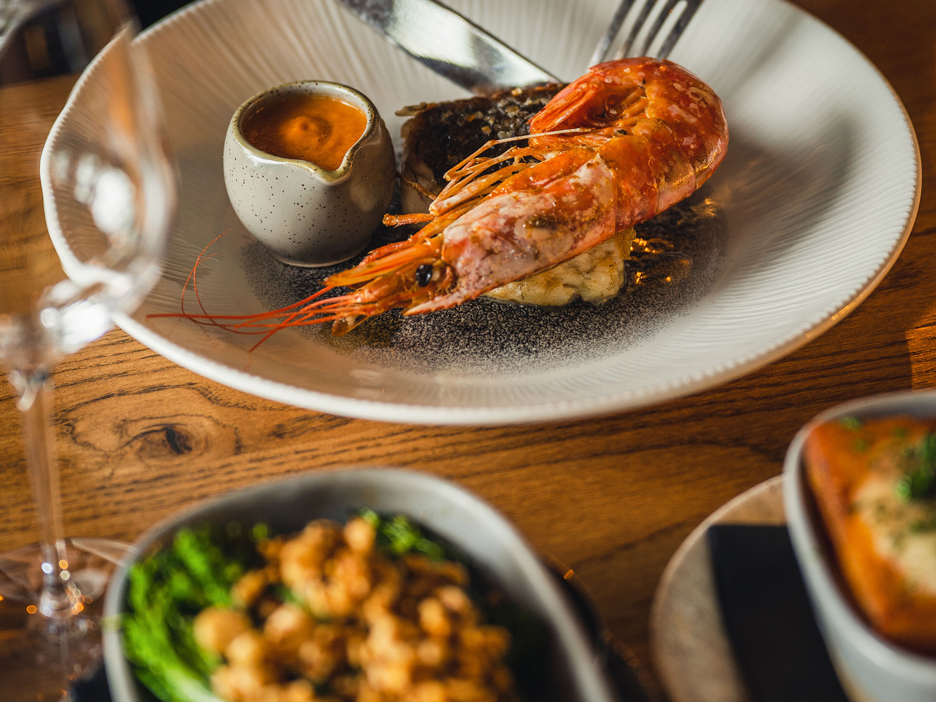 A plate of food on a table including a king prawn and a piece of cod