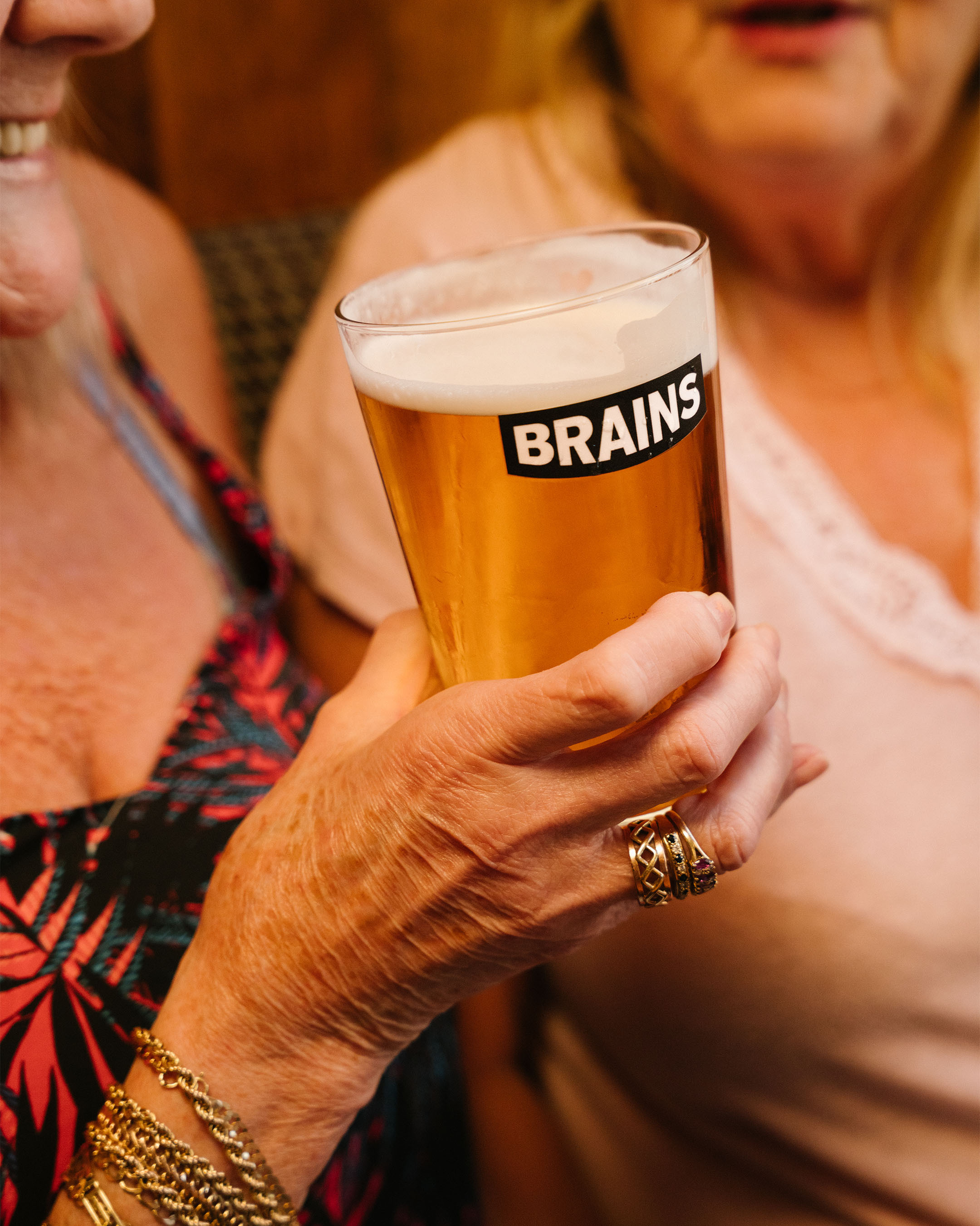 A woman holding a pint of Brains beer