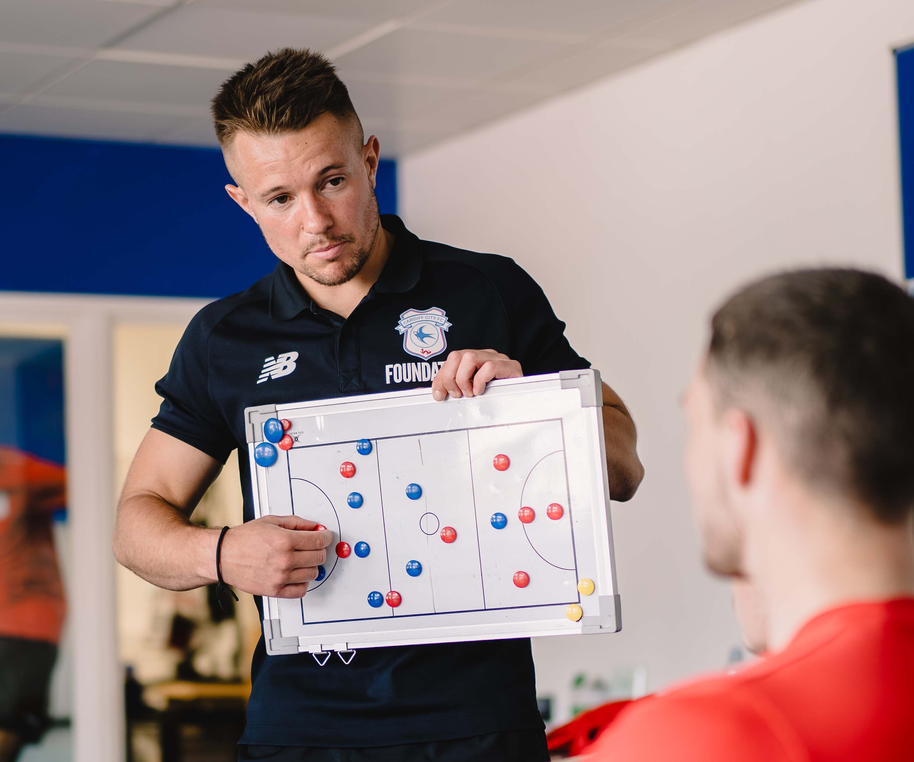 two young males playing football in a court, wearing yellow bibs