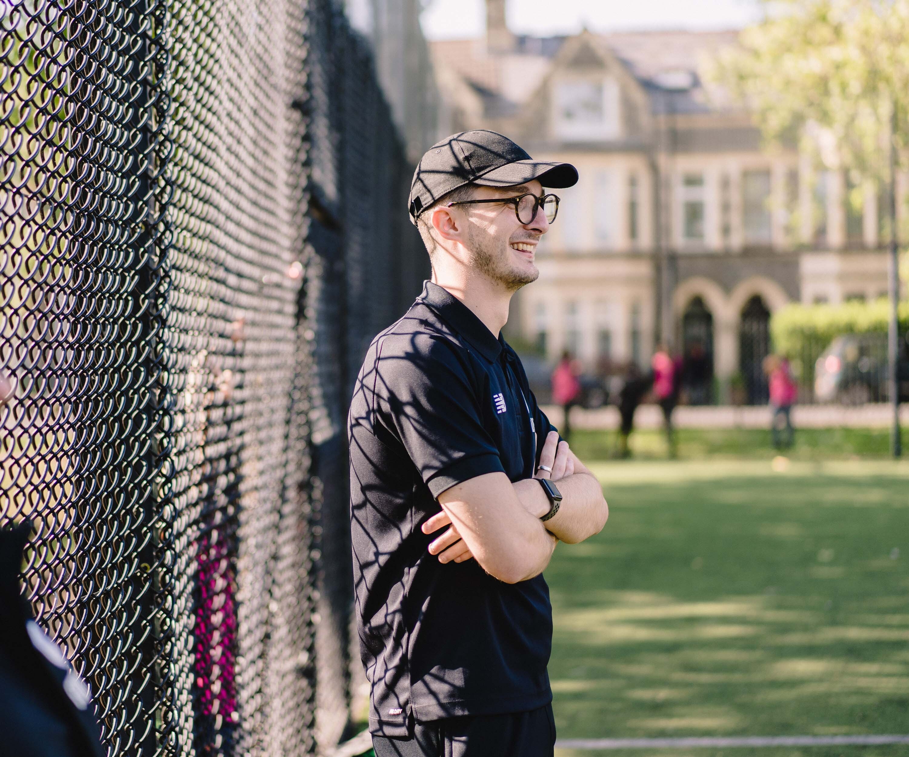 a man wearing a gap and glasses smiling watching his team play football