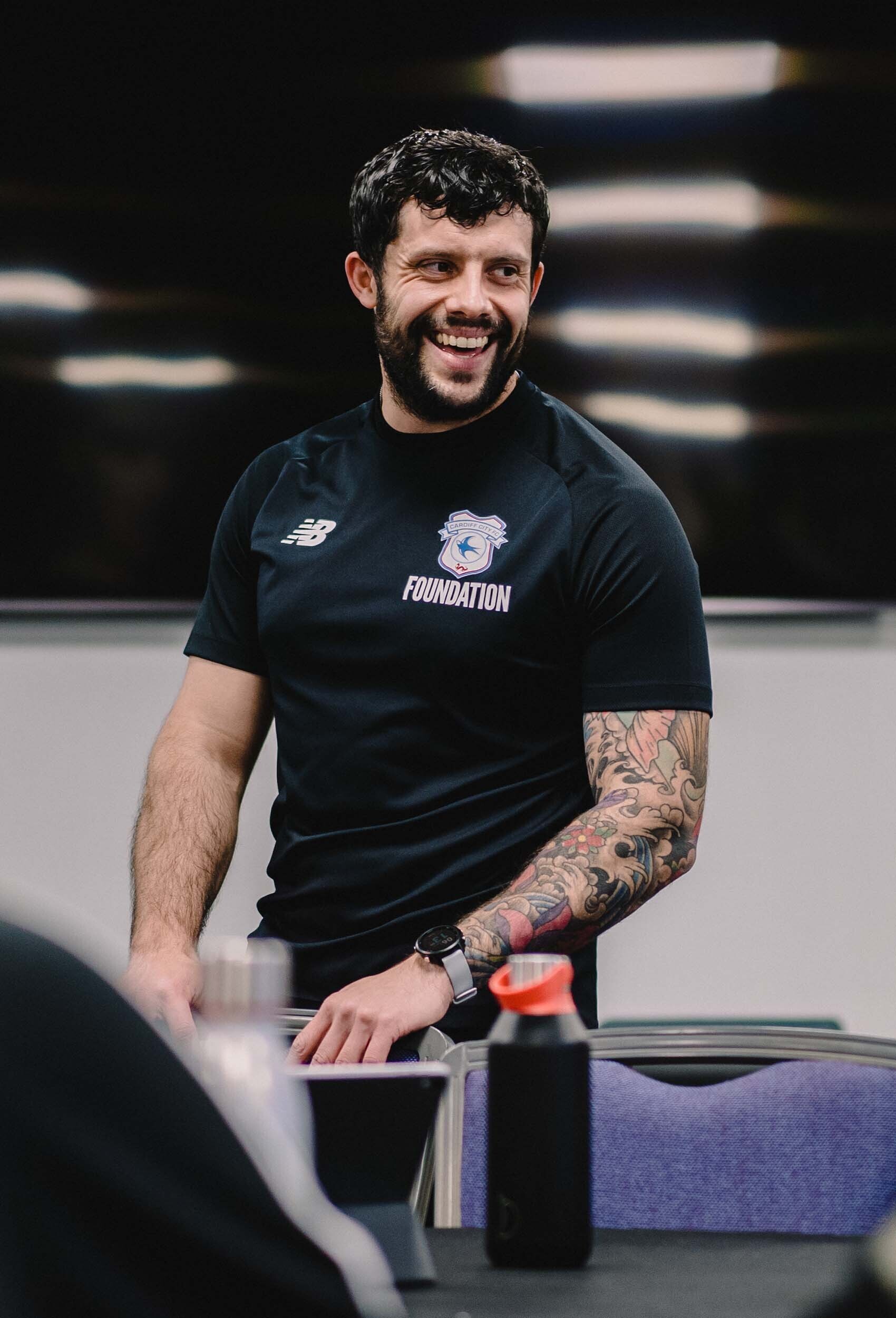 two young males playing football at a park, wearing multi coloured bibs