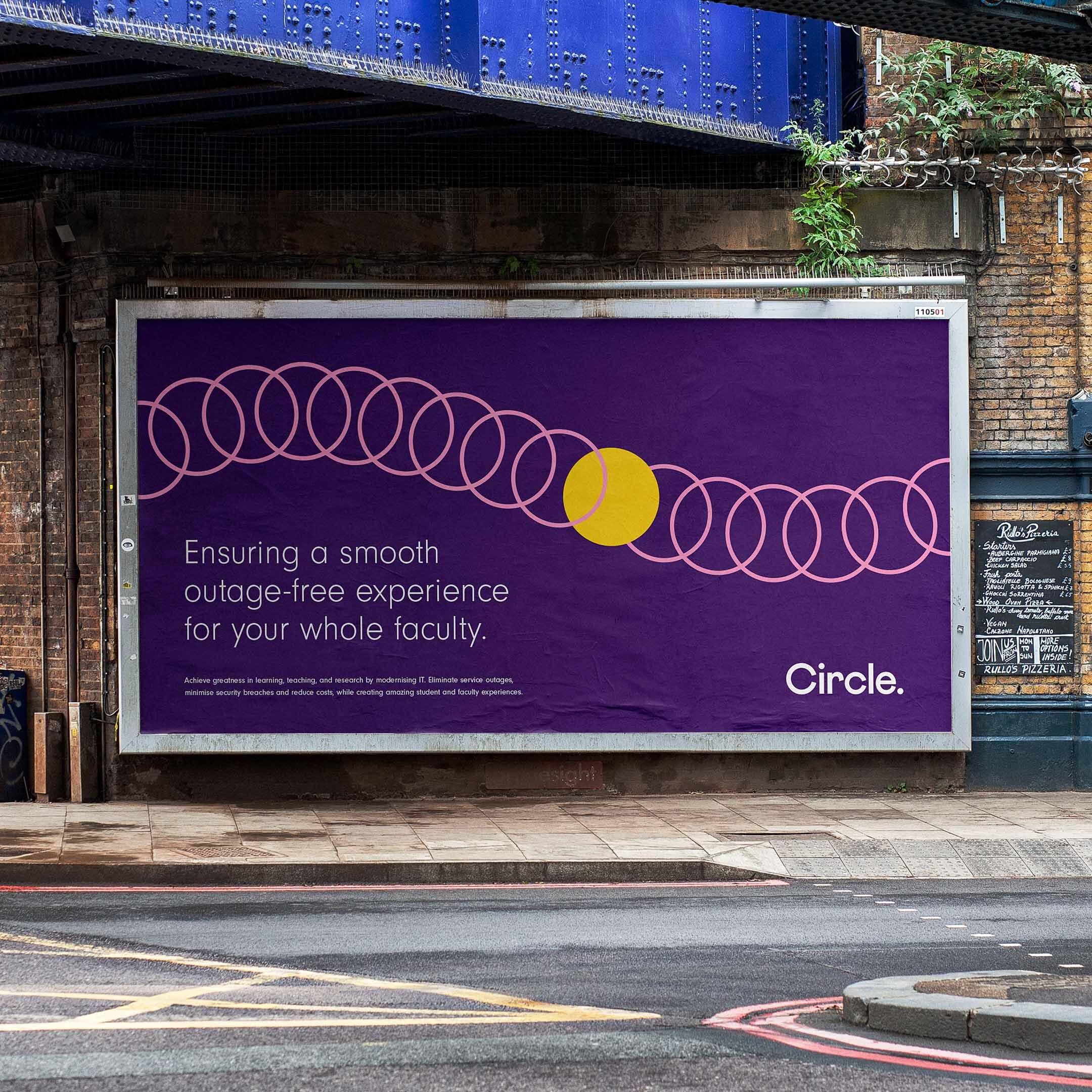 A purple Circle IT billboard under a bridge showing a colourful illustration of a yellow circle travelling through pink circles